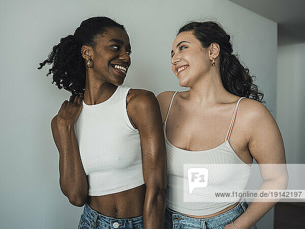 Happy young multiracial friends standing near wall