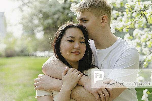 Young man embracing girlfriend at park