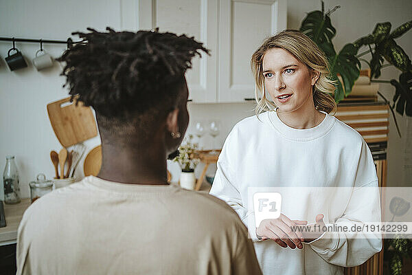 Couple standing face to face and talking in kitchen