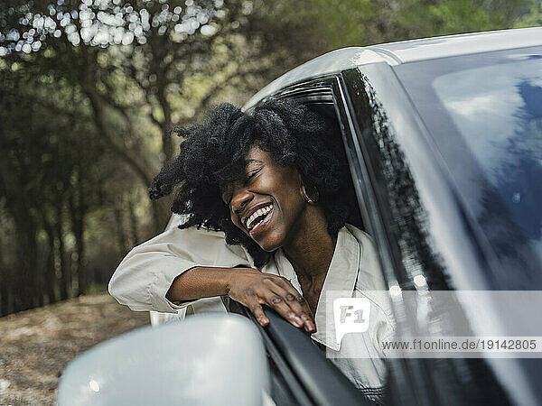 Happy woman leaning out of car window