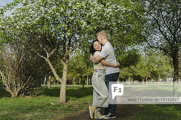 Young couple embracing each other by trees at park