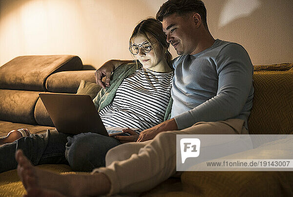 Smiling young couple using laptop together at home