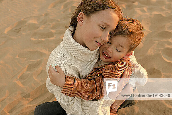 Smiling sister hugging brother at beach