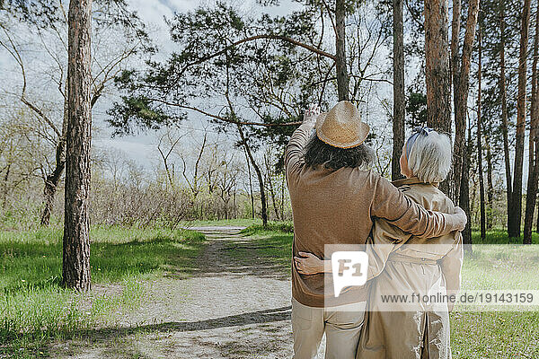 Couple with arms around exploring forest
