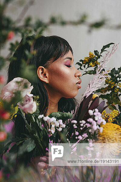 Young woman with eyes closed amidst colorful flowers