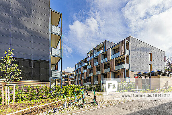 Germany  Baden-Wurttemberg  Stuttgart  Solar panels on side of modern suburban apartment buildings with rental push scooters in foreground