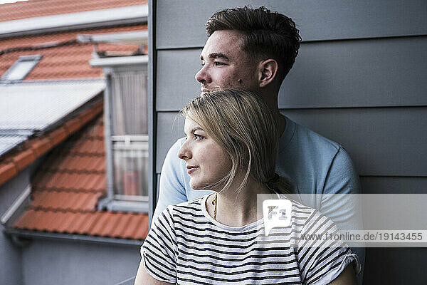 Smiling couple leaning on wall on balcony