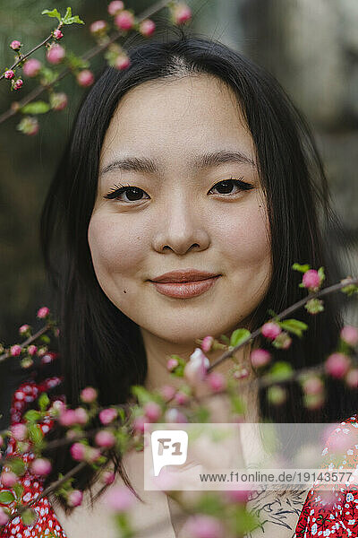 Smiling young woman by pink flowers