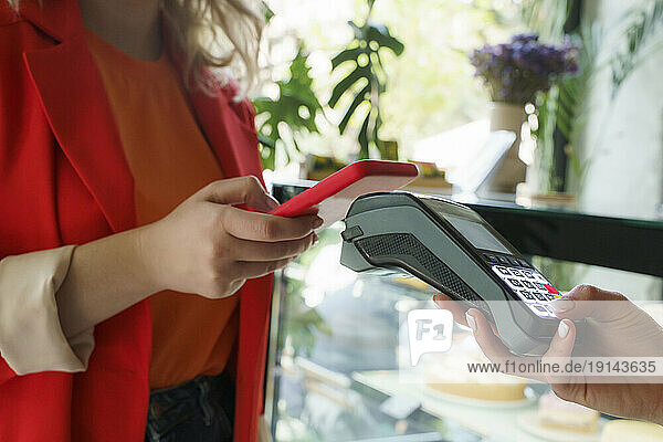 Woman paying via tap to pay method at cafe