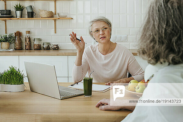 Mature nutritionist consulting client at home