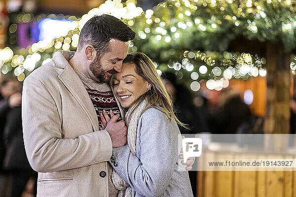 Happy loving couple hugging each other at Christmas market