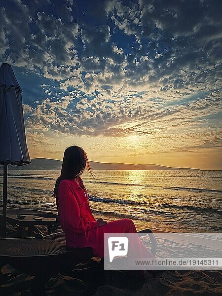 Frau entspannt auf der Sonnenliege als trifft die Morgendämmerung am Strand. Schöne Meer Sonnenaufgang Szene  Sommerurlaub am Meer  Reisen und Urlaub Entspannung Konzept
