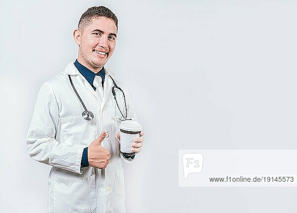 Zufriedener Arzt mit Kaffee zum Mitnehmen isoliert. Junger Arzt hält einen Kaffee zum Mitnehmen isoliert. Lächelnder Arzt hält Kaffee mit Daumen nach oben