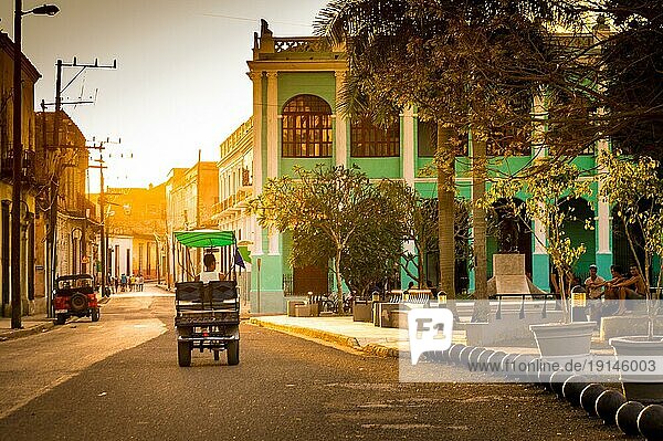 Camaguey  Kuba am 3. Januar 2016: Kuba im schönsten Licht der goldenen Stunde. Die Straßen von Camaguey sind in diesem schönen warmen Licht erleuchtet  während ein kubanisches Tuktuk vorbeifährt