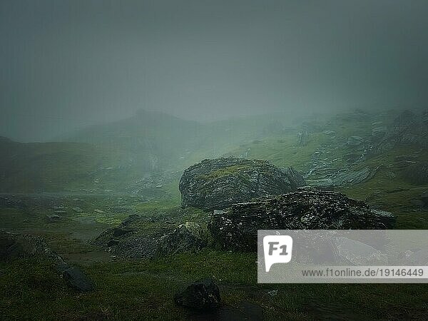 Große Bergfelsen und Felsbrocken durch den dichten Nebel gesehen. Stimmungsvolle Wanderszene bei regnerischem Wetter