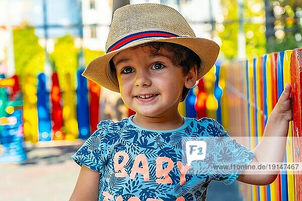 Porträt eines fröhlichen Jungen mit Hut  der auf einem Spielplatz spielt