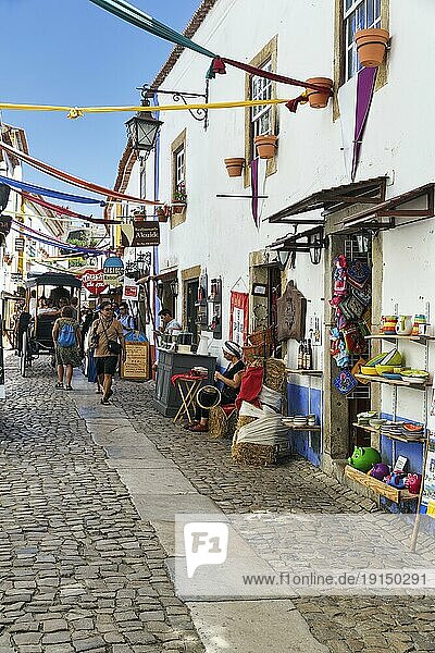 Malerische Gasse mit Geschäften und Fußgängern  Touristen im mittelalterlichen Ort Óbidos  Portugal  Europa