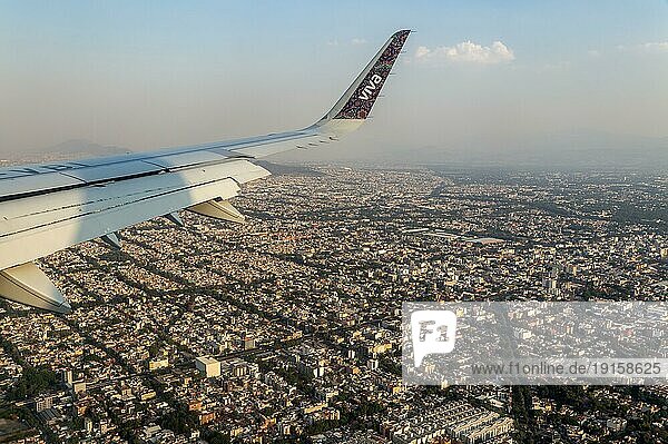 Schräge Luftaufnahme durch ein Flugzeugfenster über Mexiko Stadt  Mexiko  Flügel des Flugzeugs Viva Aerobus  Mittelamerika