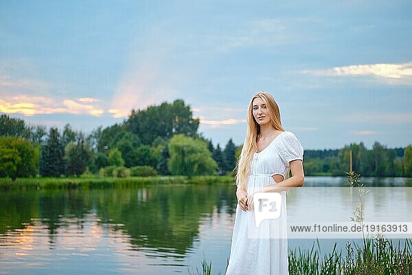 Friedliche junge Frau am Fluss stehend
