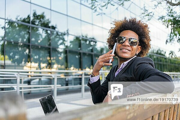 Horizontales Foto mit Kopiervorlage eines erfolgreichen Geschäftsmannes im Gespräch mit dem Handy im Freien sitzend