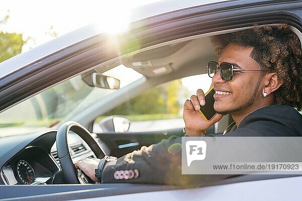 Seitenansicht eines eleganten afroamerikanischen Geschäftsmannes  der mit dem Handy spricht  das in einem Auto sitzt