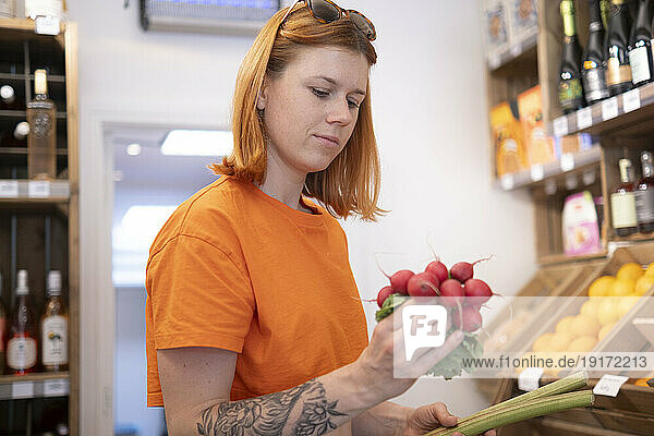 Redhead woman examining radish in store