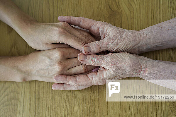 Senior woman holding hands with daughter at table