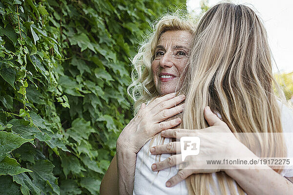 Happy senior woman hugging daughter near plants