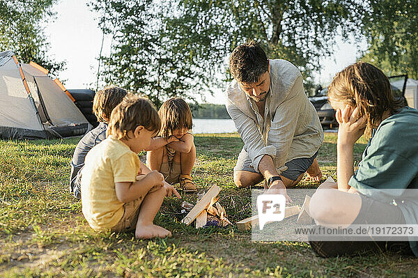 Children with father preparing for bonfire on grass