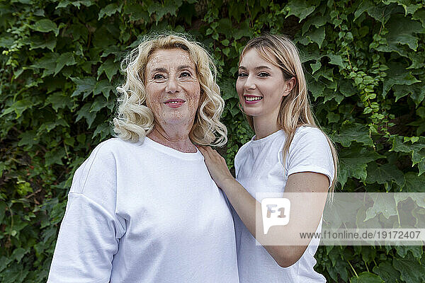 Happy beautiful woman standing with mother in front of plants