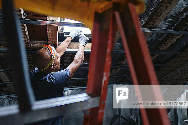 Construction worker repairing ceiling window in attic