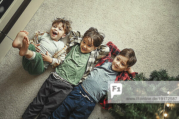 Brothers lying on carpet near Christmas tree at home