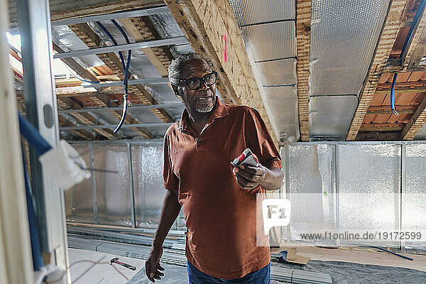 Senior man standing in attic at site