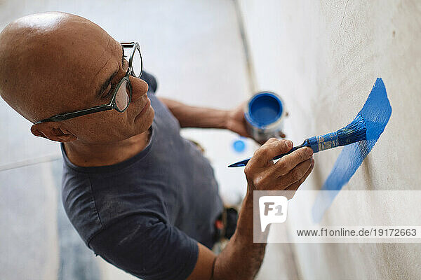 Construction worker painting wall with brush at site