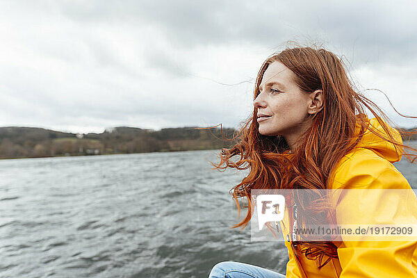 Thoughtful redhead woman looking at lake