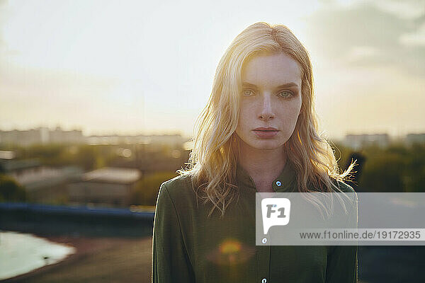 Young blond woman on roof at sunset