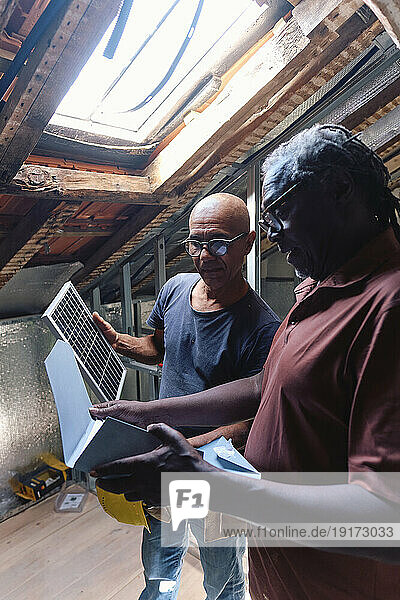 Architect and builder with solar panel discussing and planning over document at site