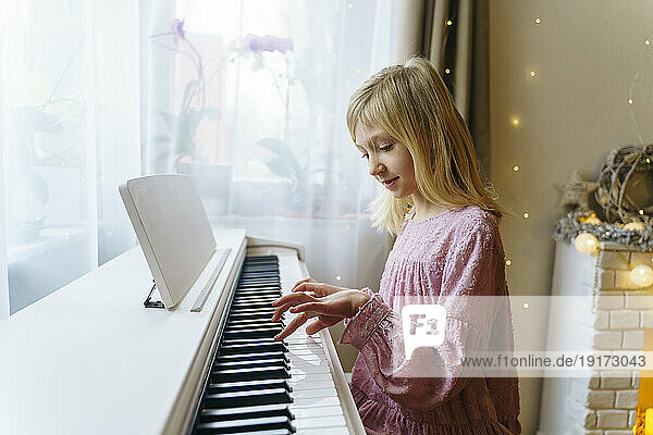 Blond girl playing piano at home on Christmas