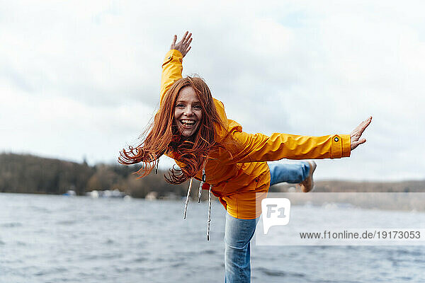Happy woman with arms outstretched enjoying at lake