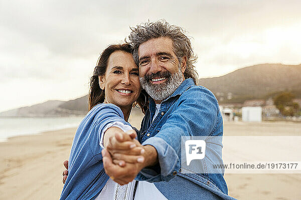 Happy loving couple holding hands at beach