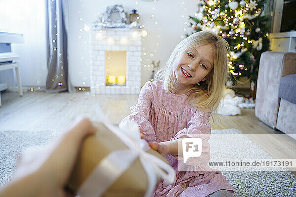 Blond girl receiving Christmas present from brother at home