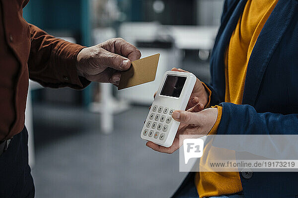 Hand of businessman doing contactless payment at work place