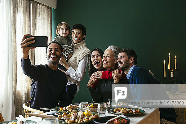 Smiling family taking selfie on smart phone at home
