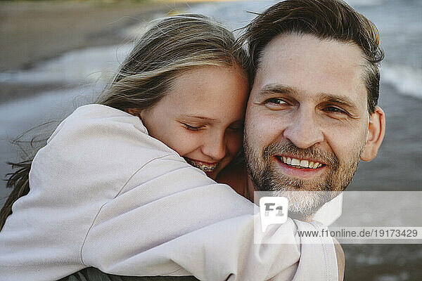 Happy daughter hugging father at beach
