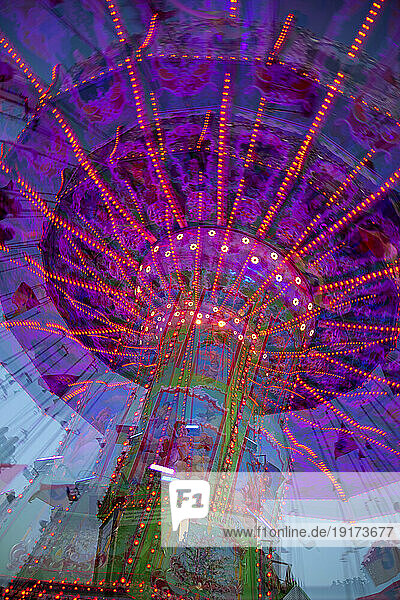Germany  Bavaria  Wurzburg  Multiple exposure of spinning carousel at dusk