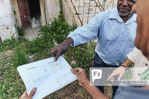 Architect having discussion over blueprint with client at site