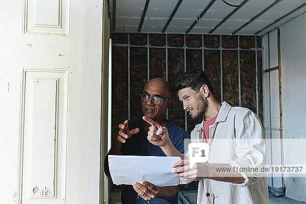 Happy architect discussing over document with man gesturing at site