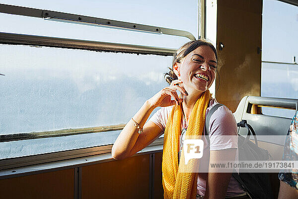 Happy woman sitting in train next to window