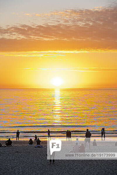 Germany  Schleswig-Holstein  Sun setting over people on sandy beach of Sylt island