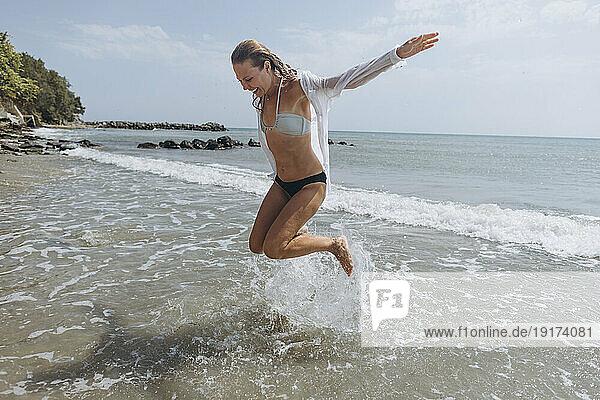 Happy woman jumping at beach